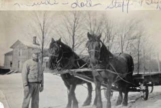 Man standing beside horse drawn wagon